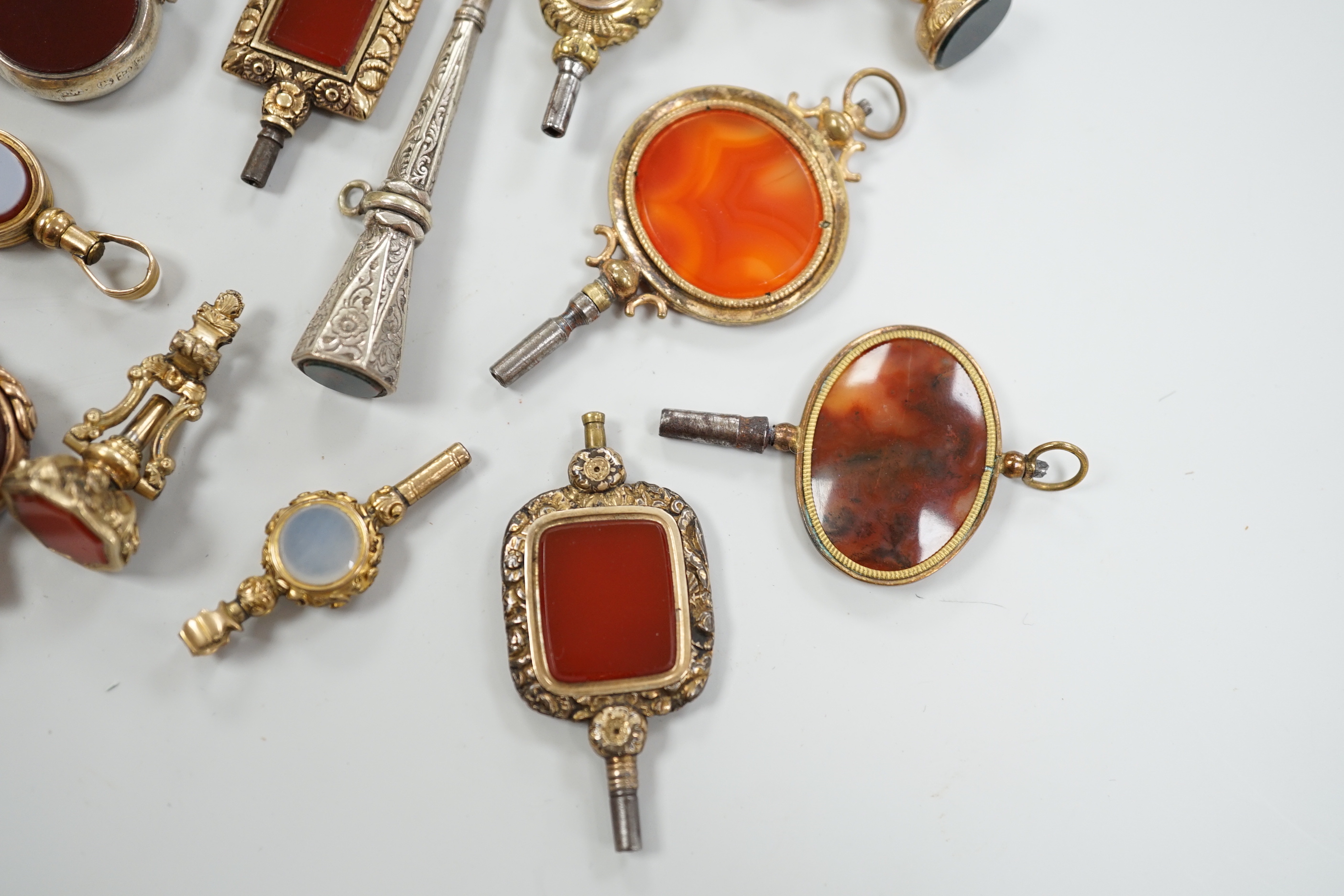 Sixteen assorted 19th century and later, 9ct gold and yellow or white metal overlaid and chalcedony set watch keys, including bloodstone, sardonyx, banded agate and moss agate and spinning fobs, largest 56mm.